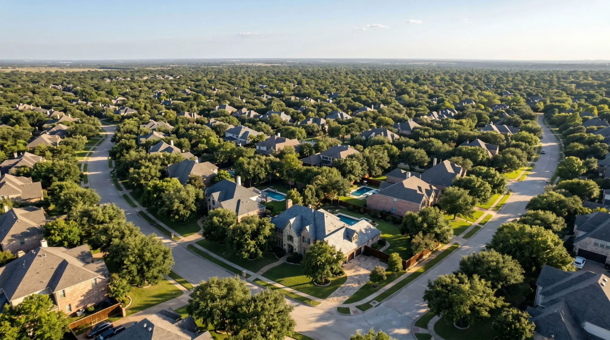 Aerial view of an affluent North Texas neighborhood with mature live oak canopy, large lots, and curving streets — the visual signature of DFW old-money enclaves.