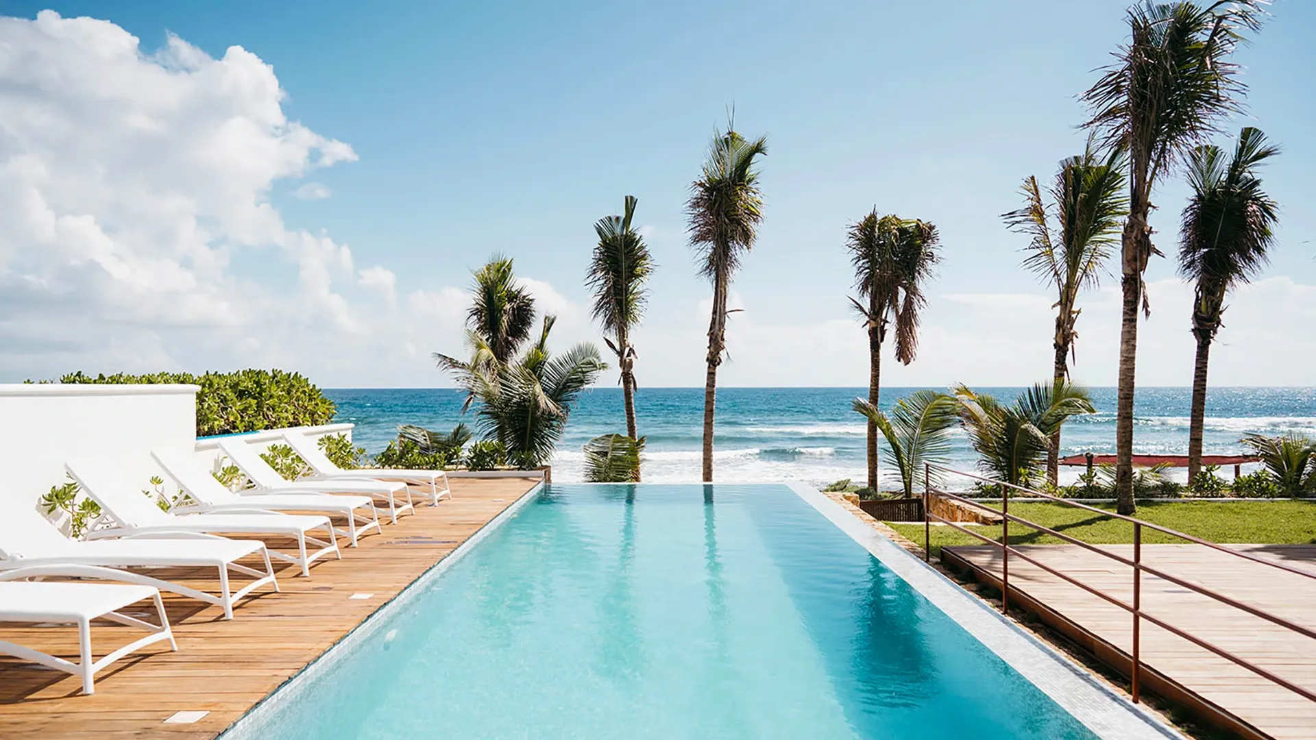 Villa Matara's beachfront infinity pool on Tankah Beach near Tulum, with sun loungers and palms overlooking the Caribbean.
